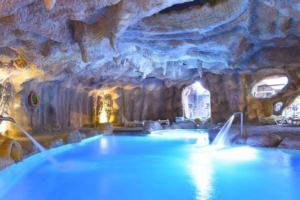 Unterirdischer Pool im Parrotel Beach Resort mit blau beleuchtetem Wasser und steinerner Decke.