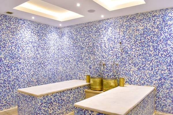 Innenansicht der Sauna im Parrotel Beach Resort mit blauen Fliesen und goldenen Accessoires.