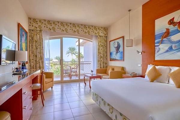 Ein modernes Hotelzimmer im Parrotel Beach Resort mit Blick auf eine Terrasse und eine grüne Landschaft.