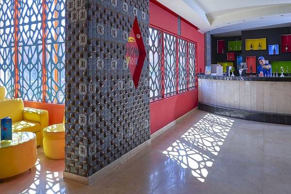 Empfangsbereich des Parrotel Beach Resorts mit gelben Möbeln, roter Wand und geschnitztem Wandmuster.