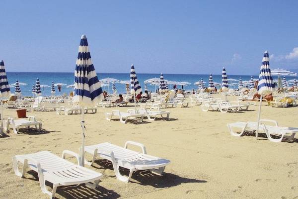 Strand des Falkensteiner Club Funimation Garden Calabria mit vielen Liegestühlen und Sonnenschirmen.