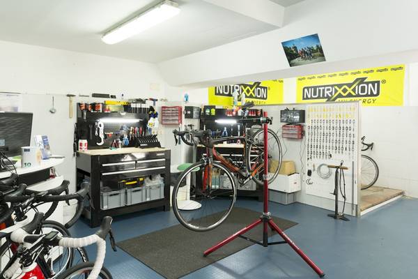 Ein Fahrrad-Reparaturbereich mit mehreren Fahrrädern, Werkzeugen und Bannern.