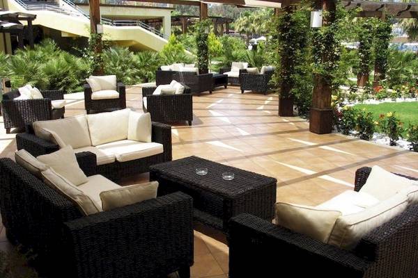Außenbereich des Falkensteiner Club Funimation Garden Calabria mit Rattanmöbeln und Pflanzen.