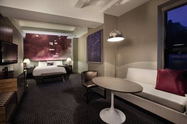 Hyatt Grand Central New York Zimmer mit Bett, Couch, Tisch, Lampe und Fernseher.