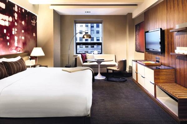 Ein modernes Hotelzimmer im Hyatt Grand Central New York mit einem großen Bett, einem Fernseher und einer Sitzecke.