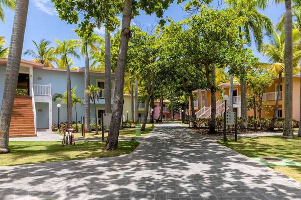 Eingang des Playabachata Spa Resorts mit bunten Gebäuden und Palmen.