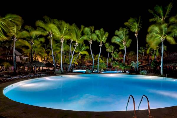 Nachtlicher Pool im Playabachata Spa Resort mit leuchtend blauem Wasser und umgeben von Palmen.