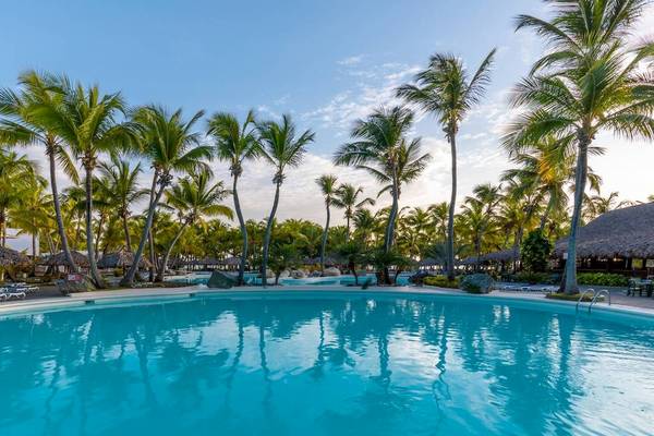 Poollandschaft des Playabachata Spa Resorts mit Palmen und Sonnenliegen.