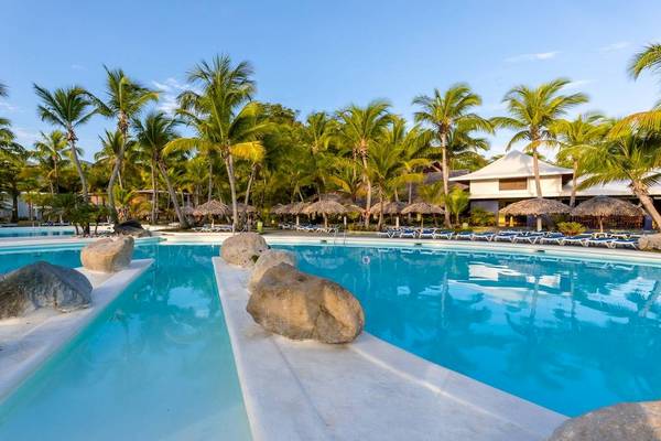 Pool im Playabachata Spa Resort Hotel mit Liegestühlen und Palmen.