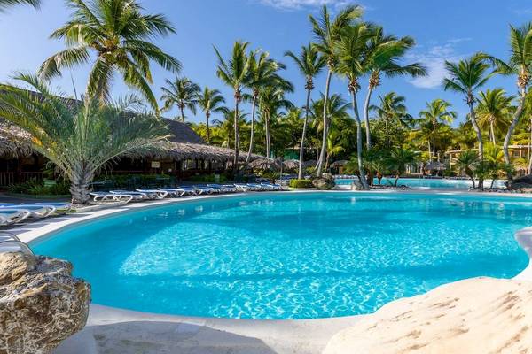 Ein Swimmingpool im Playabachata Spa Resort mit Palmen und Liegestühlen.