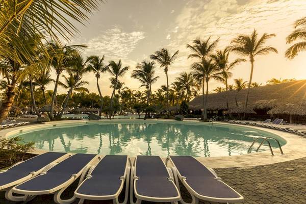 Pool am Sonnenuntergang im Playabachata Spa Resort mit Palmen und Sonnenliegen
