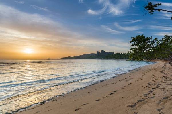 Sonnenuntergang am Strand des Playabachata Spa Resorts mit ruhigem Meer und Fußspuren im Sand.