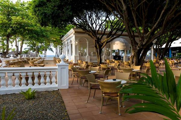Terrasse des Playabachata Spa Resorts mit vielen Sitzgelegenheiten unter Bäumen.