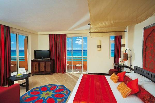 Hotelzimmer im SALT of Palmar mit Meerblick, rote Vorhänge und Bett, Fernseher und Tisch mit Balkon.