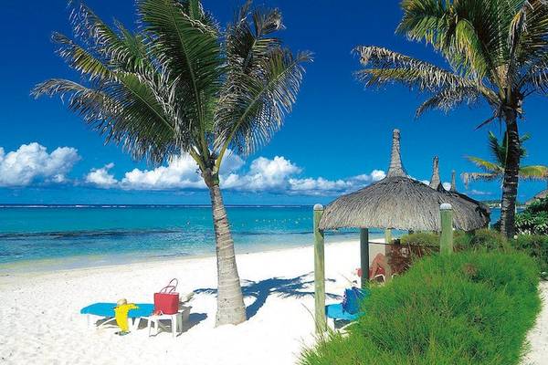 Sandstrand mit Palmen und Sonnenhut, wo ein Hotelgast entspannt