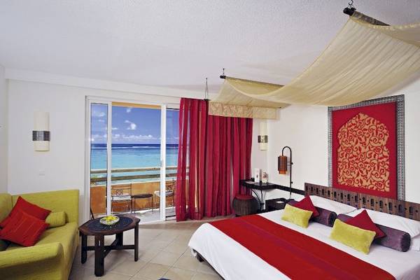 Hotelzimmer im SALT of Palmar mit Blick auf das Meer, mit einem großen Bett, einem grünen Sofa und einem Tisch davor.