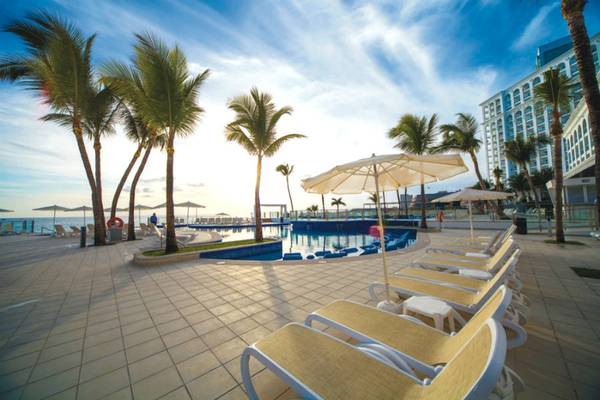 Poolbereich des Riu Cancun Hotels mit Liegestühlen, Sonnenschirmen und Palmen
