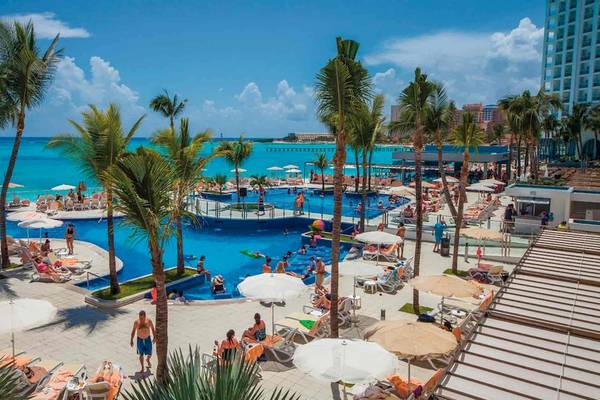 Luftaufnahme des großen Pools im Riu Cancun Hotel mit vielen Gästen und Palmen.