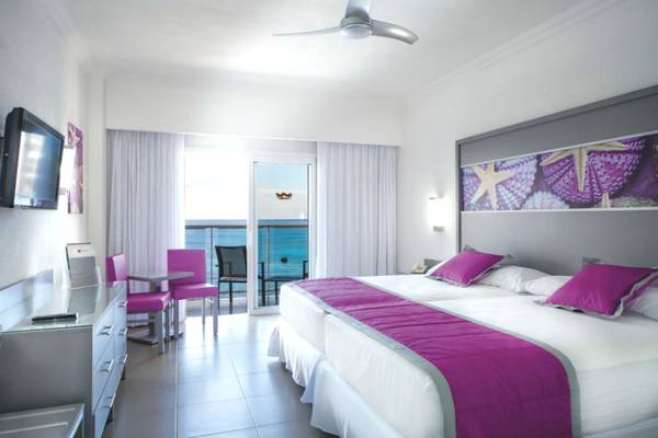 Innenansicht eines Hotelzimmers im Riu Cancun mit Blick auf das Meer und eine Terrasse.