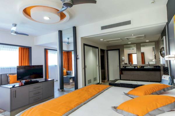 Innenansicht eines Hotelzimmers im Riu Cancun mit Fernseher, Bett und Badezimmer.