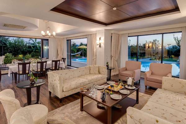 Innenansicht des Wohnbereichs im Susesi Luxury Resort mit Sofas, Tisch und Poolsicht.