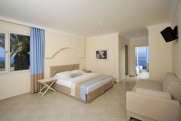Innenansicht eines Hotelzimmers im Club Resort Atlantis mit einem Bett, einem Sofa und einer Aussicht auf das Meer.