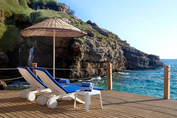 Terrasse des Club Resort Atlantis mit zwei Liegen und einem Sonnenschirm am Meer