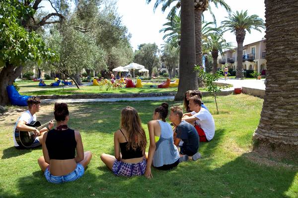 Gruppe Jugendlicher im Club Resort Atlantis spielen Musik und unterhalten sich im Freien.