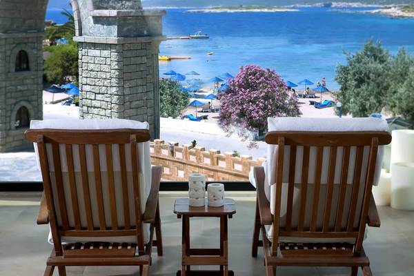 Blick vom Club Resort Atlantis auf den Strand mit Loungesesseln und einem Tisch dazwischen.
