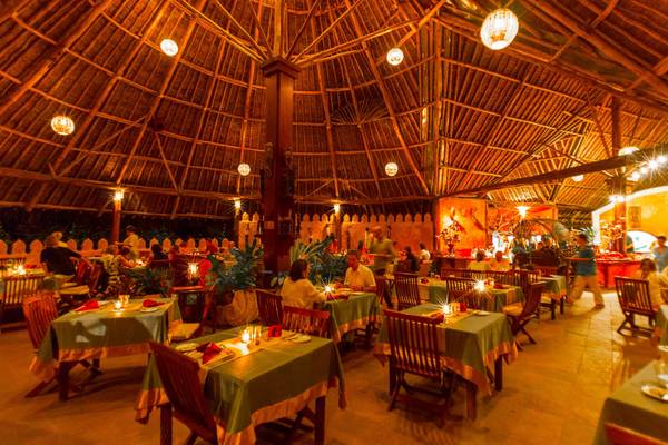 Innenbereich des Restaurants im Sands at Chale Island Resort mit beleuchteten Tischen und Stühlen.