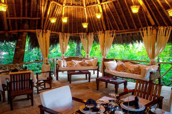 Innenbereich des Sands at Chale Island Resort mit gepolsterten Sofas, Tischen und Stühlen.