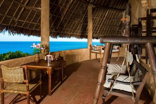 Balkon mit Meerblick im Sands at Chale Island Resort, mit Tisch, Stühlen und Hängesessel.