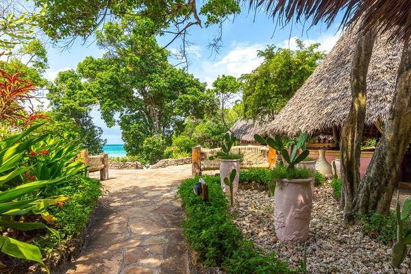Gartenweg mit Blick auf das Meer, Hutdach und Pflanzenkübel im Sands at Chale Island Resort.