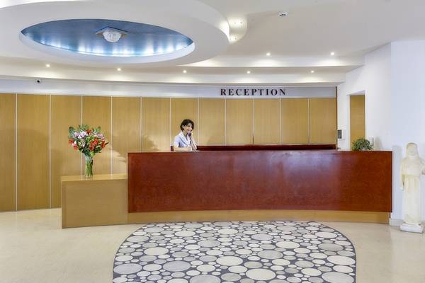 Receptionsbereich des Astir Beach Hotels auf Kreta mit Angestellter und Blumenvase.