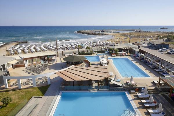 Luftaufnahme des Astir Beach - Kretas Resorts mit zwei Swimmingpools, Sonnenliegen und Sonnenschirmen am Strand.