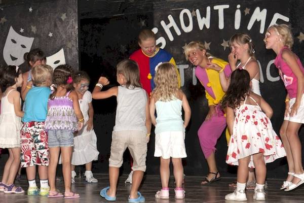Gruppe von Kindern und zwei Erwachsenen in Showkostümen auf einer Bühne des Astir Beach Hotels in Kreta.