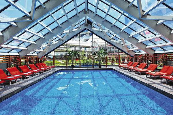 Innenpool des Susesi Luxury Resorts mit roten Liegestühlen und Glasdach.