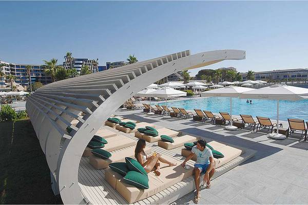 Luftaufnahme des Poolbereichs im Susesi Luxury Resort mit Loungesofas und Sonnenschirmen.