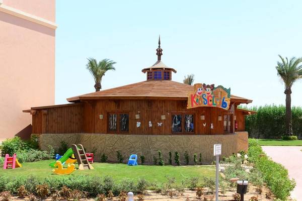 Außenansicht des Charmillion Club Aqua Parks mit bunten Spielgeräten und einer beschrifteten Kinderclub-Hütte.