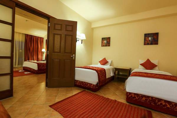 Hotelschlafzimmer des Charmillion Club Aqua Park mit zwei Betten, Tisch und Bildern an der Wand.