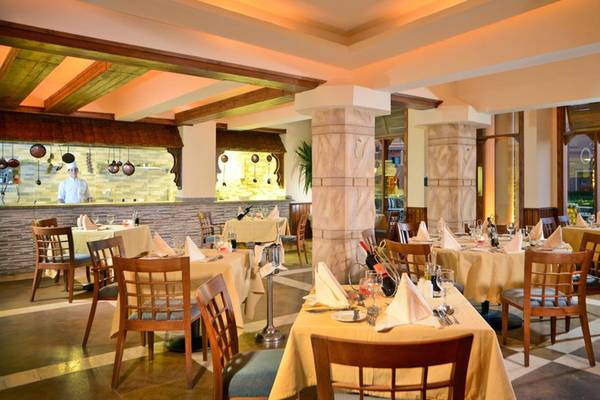 Innenansicht des Restaurants im Charmillion Club Aqua Park mit gedeckten Tischen und einem Koch hinter der Theke.