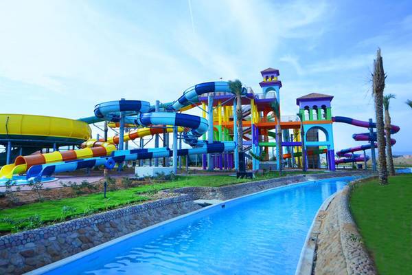 Farbige Wasserrutschen im Charmillion Club Aqua Park neben einem großen Schwimmbecken.