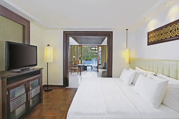 Schlafzimmer im Melia Bali Hotel mit Fernseher und offenem Balkon.