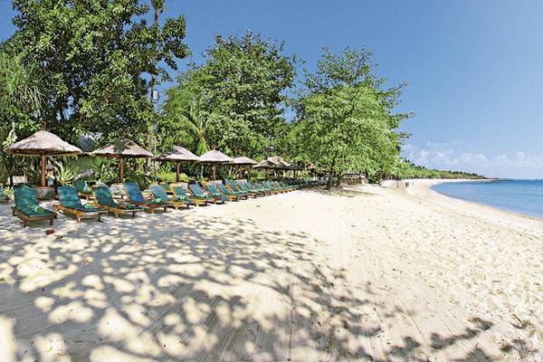 Strand des Melia Bali Hotels mit Sonnenliegen und Sonnenschirmen.