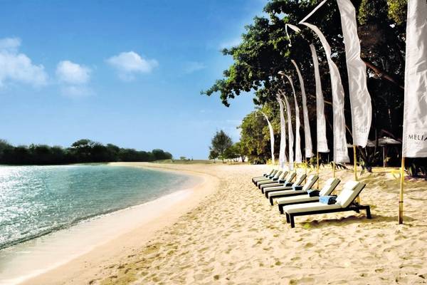Strand mit Loungesesseln und weißen Fahnen am Melia Bali Hotel.