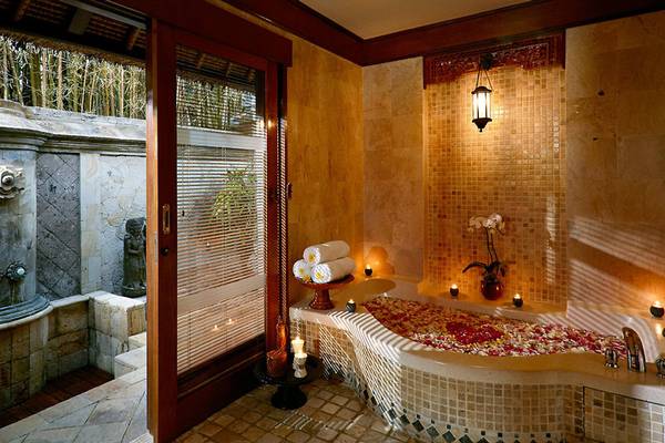 Ein Badezimmer im Melia Bali Hotel mit Badewanne, Blumen und Kerzen.