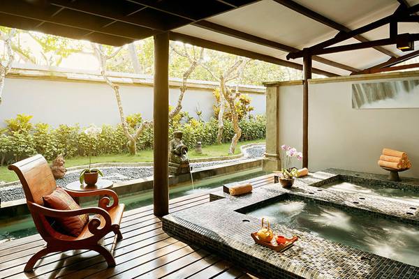 Außen-Jacuzzi auf der Terrasse des Melia Bali Hotels mit Gartenblick und Wasserfall.