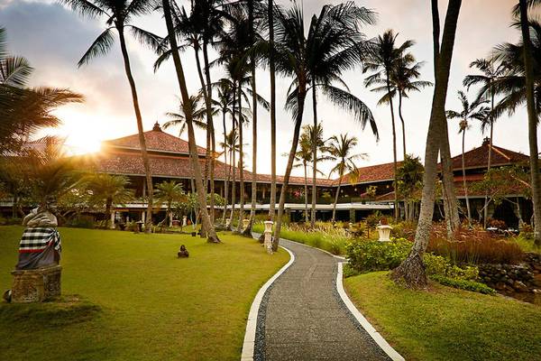 Sonnenuntergang am Melia Bali Hotel mit gepflastertem Weg und Palmen