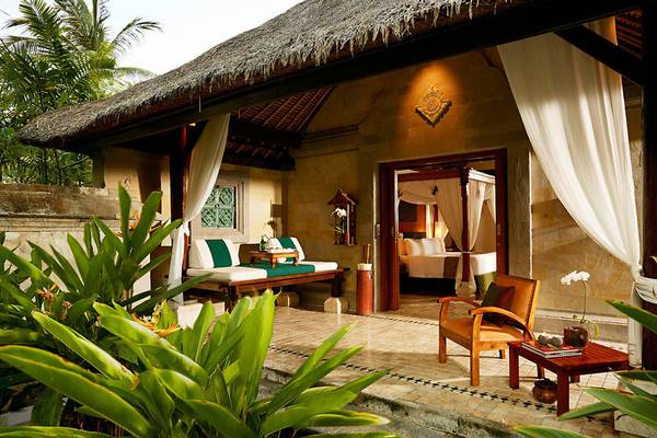 Außenbereich der Melia Bali Villa mit grünem Bett, Stuhl und Tisch im Freien.