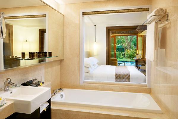 Badezimmer im Melia Bali Hotel mit Blick auf das Bett und den Garten